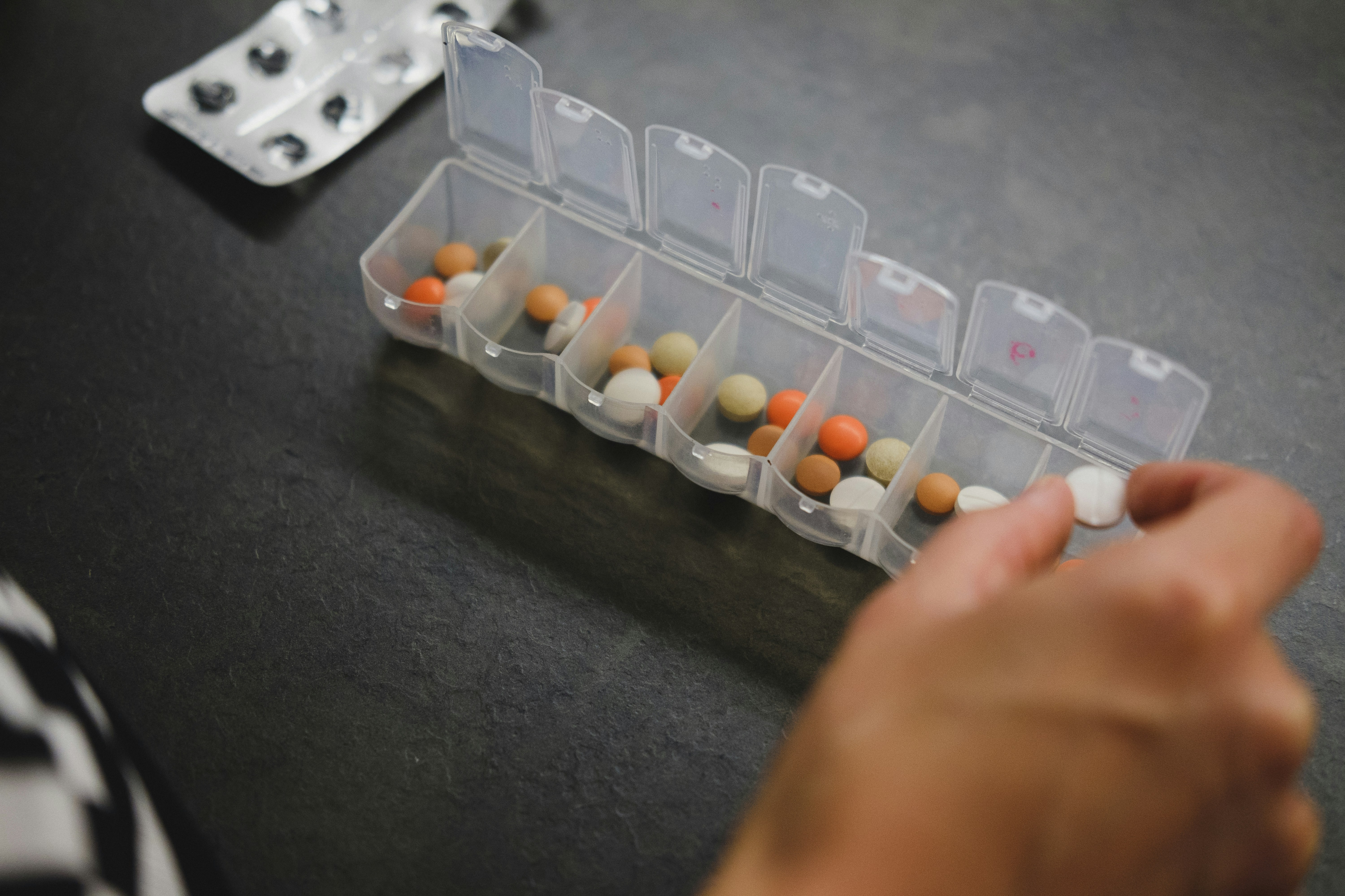 Hand sorting medication into a weekly pill organizer